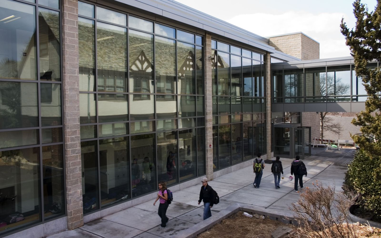 Exterior of Dwight-Englewood School’s Klein Campus Center, with students walking beside its glass façade